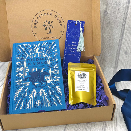 Book gift set with 'The Dark is Rising' book, hot chocolate and bookmark in a box labeled 'Paperback Down'.