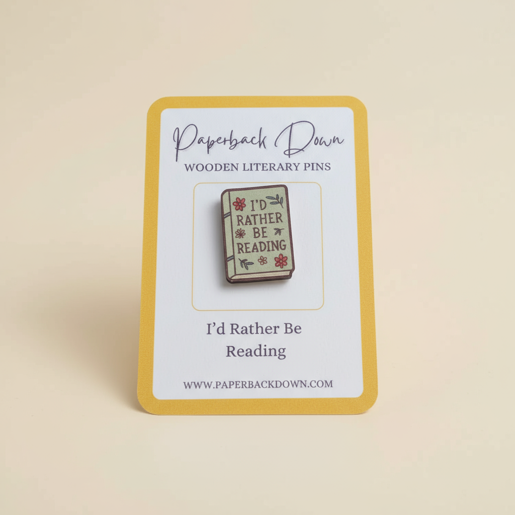 Wooden literary pin with 'I'd Rather Be Reading' text on a card, branded 'Paperback Down'.