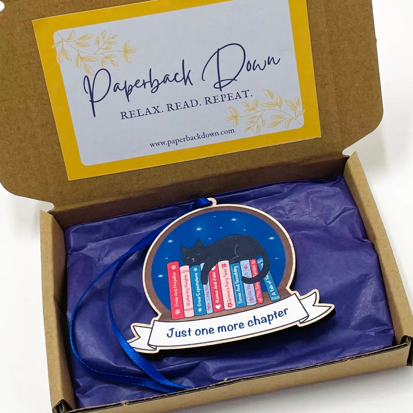 Decorative ornament with a cat and books design in a 'Paperback Down' box.