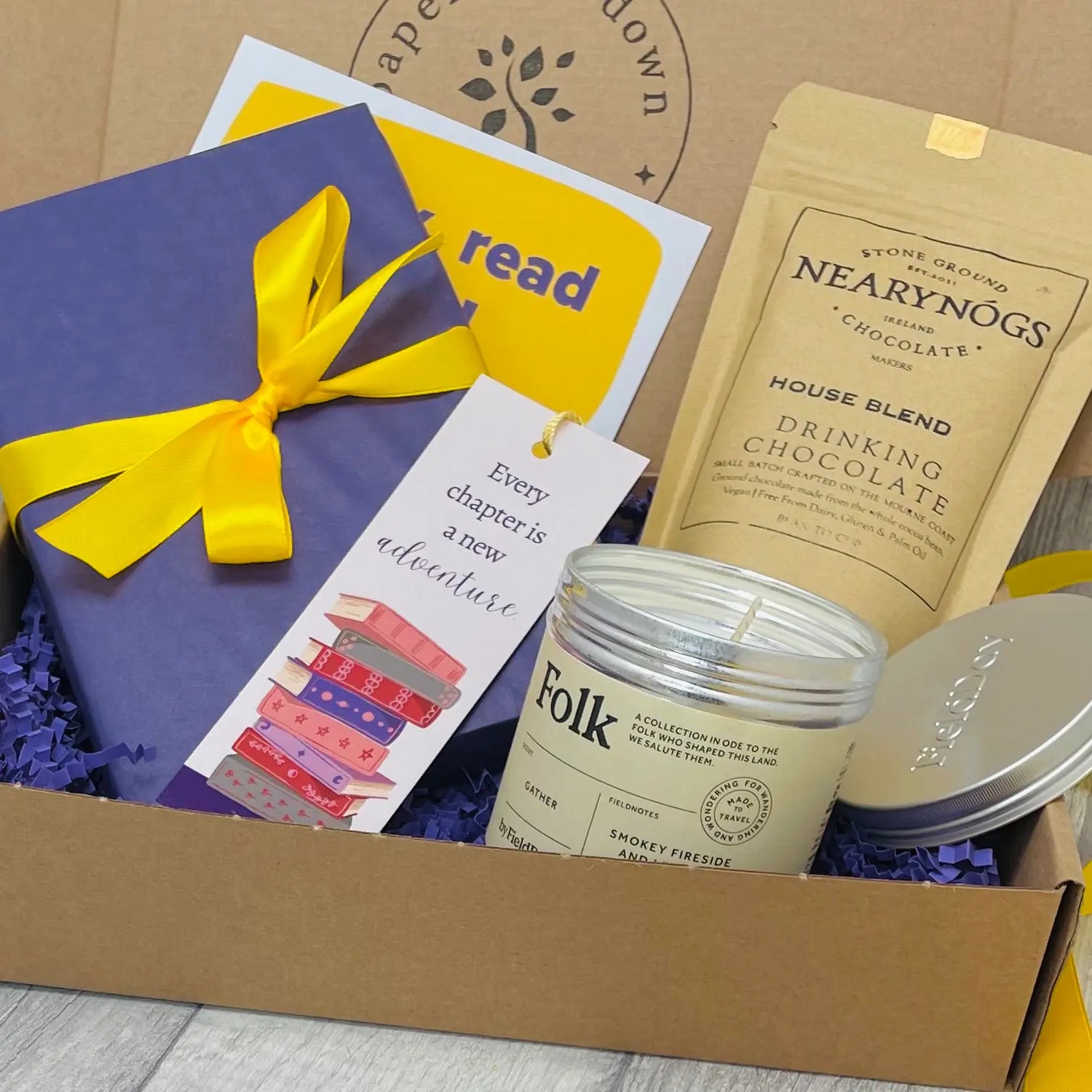 A beautifully wrapped gift box with a new paperback, scented candle and delicious hot chocolate