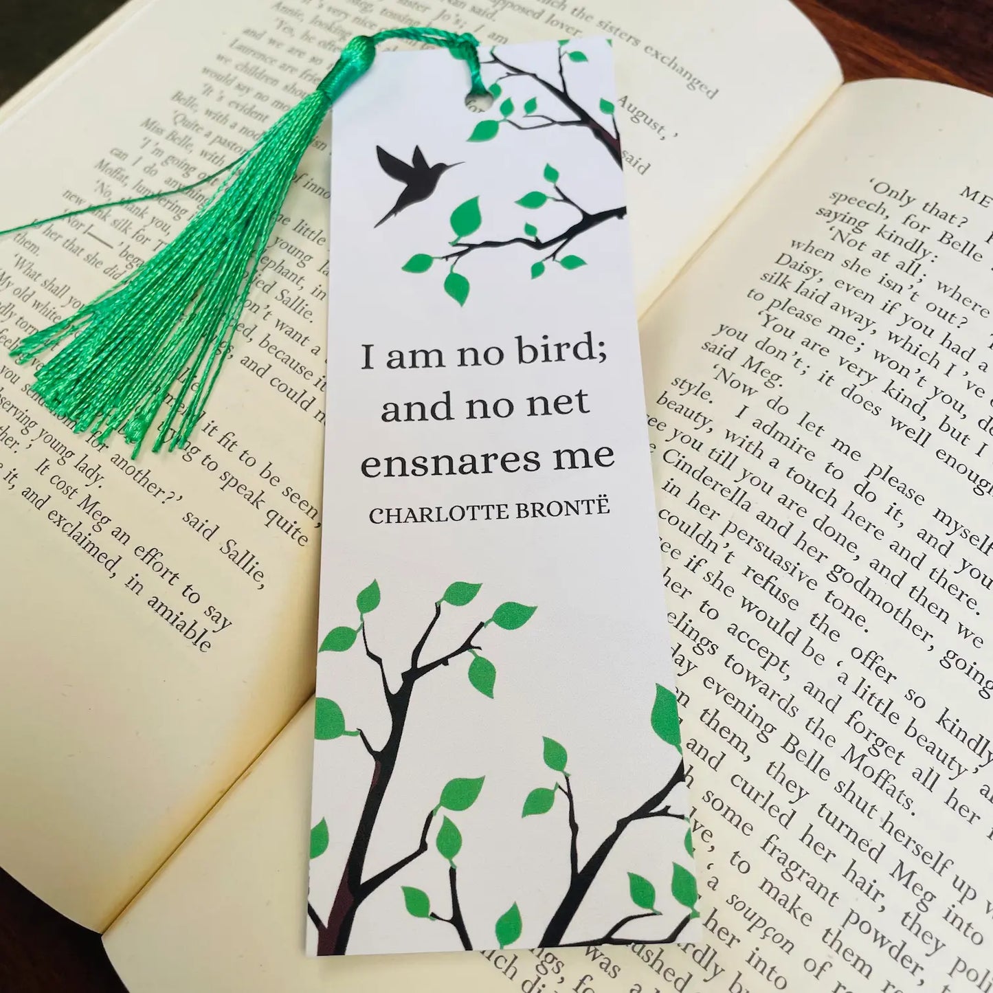 Image shows a white and green bookmark with an image of a bird flying towards tree branches. In the centre is Charlotte Bronte's iconic quote from Jane Eyre 'I am no bird; and no net ensnares me'.