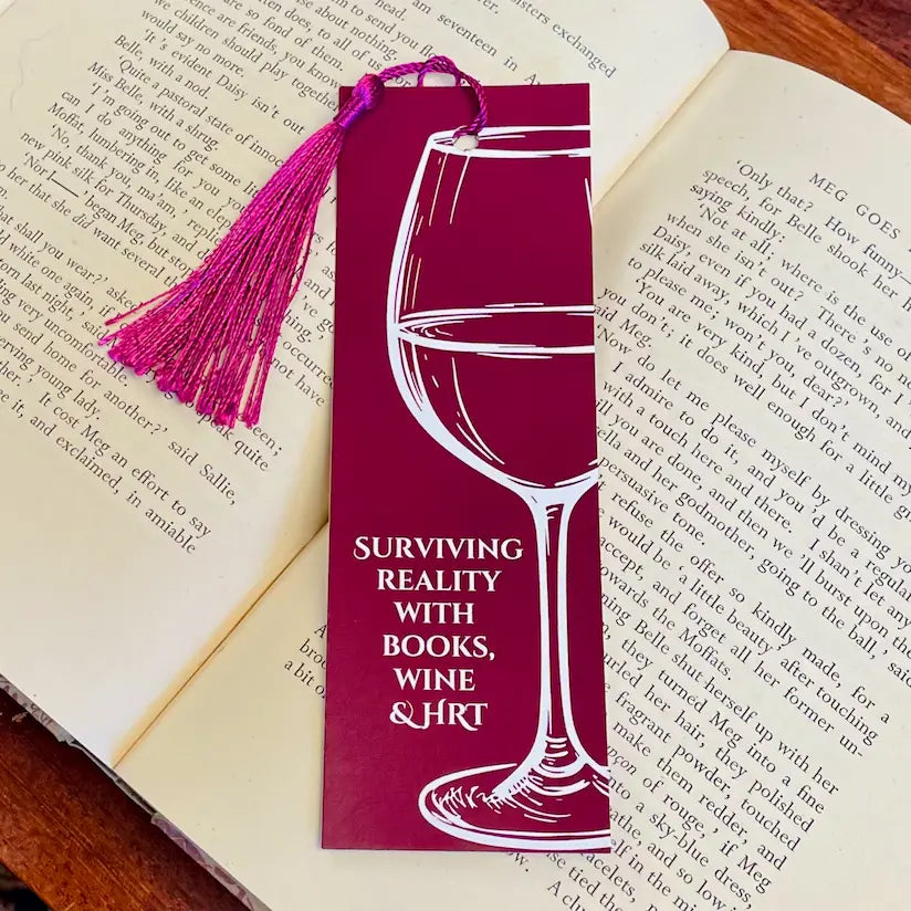 Relatable and funny bookmark for anyone menopausal or peri-menopausal, in a dark red background with a wine glass design and text saying 'Surviving reality with books, wine and HRT'.