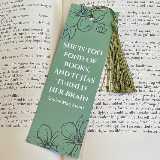 Green bookmark with a floral print and the book quote "She is too fond of books, and it has turned her brain" by Little Women author Louisa May Alcott.