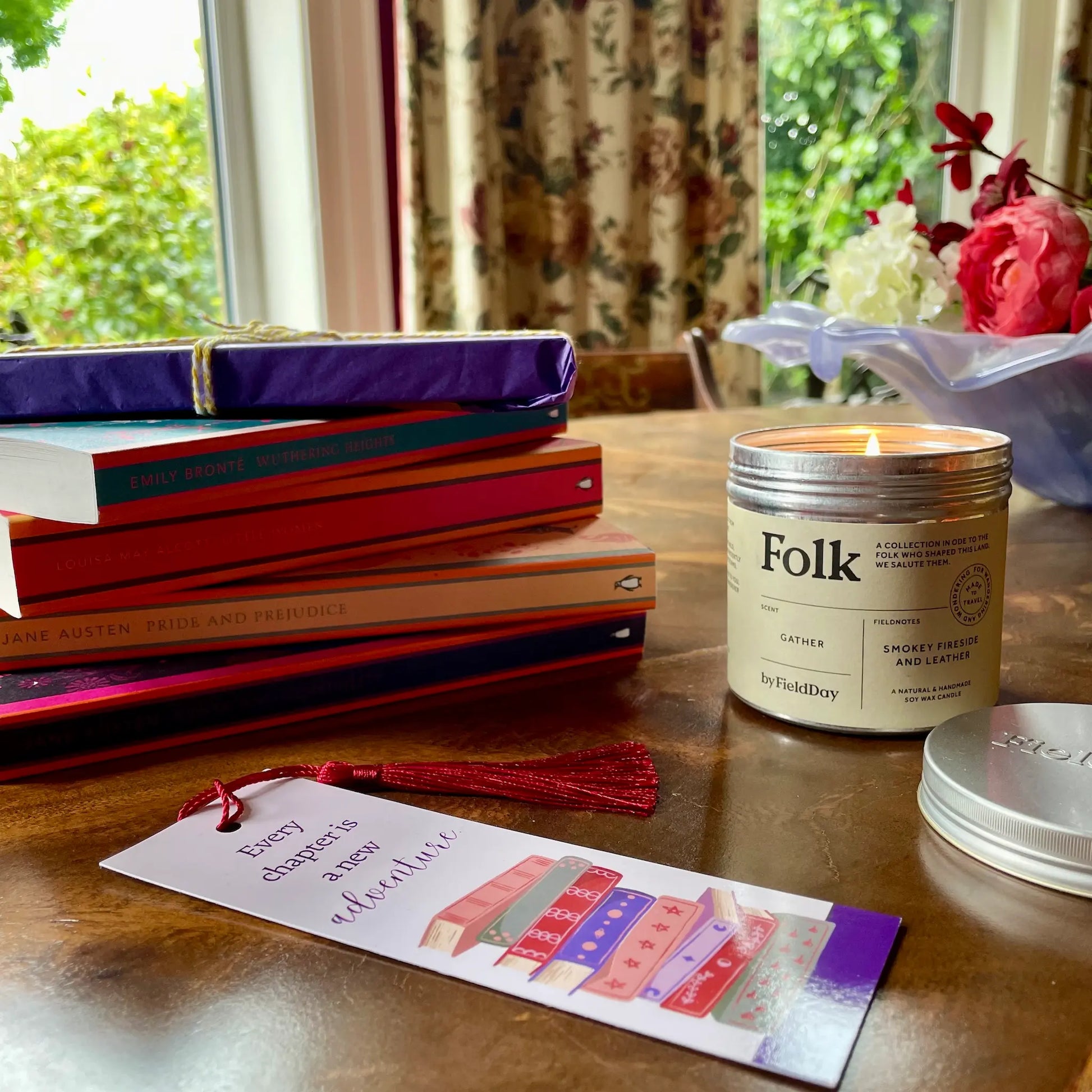 Image shows a classic book and candle gift set for book lovers. Pictured is a stack of collectible Penguin English Library paperbacks, classic and timeless fiction from across the century. Also shown is a Field Day Gather Folk Tin Candle, hand poured in County Down