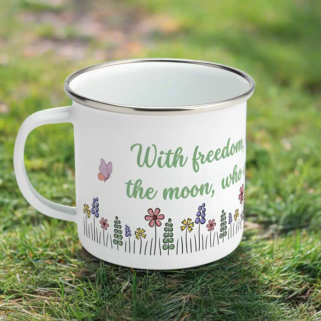White enamel mug with floral design and a book quote by Oscar Wilde, sitting on a grassy lawn