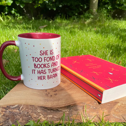 Images show a red and white ceramic mug for book-lovers featuring the quote from Little Women , 'She is too fond of books and it has turned her brain'. Beside the mug is a Penguin English Library Edition of the mug itself.