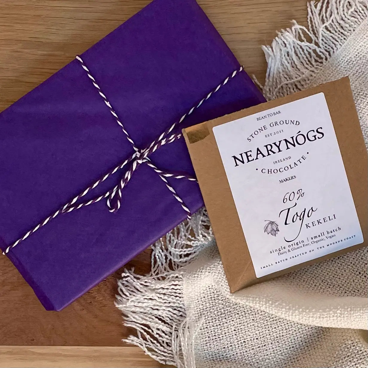 A book subscription box with chocolate - image shows a beautifully wrapped book, plus a bar of luxury artisan chocolate. typical of what would be received in this monthly gift for readers and book lovers