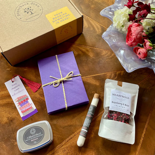 A self-care gift box for booklovers containing a surprise new paperback, relaxing bath salts, a soothing body lotion bar and delicious NearyNogs chocolate slates