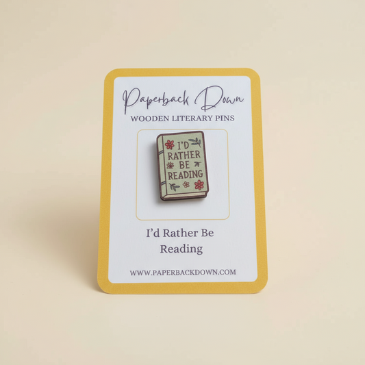 Wooden literary pin with 'I'd Rather Be Reading' text on a card, branded 'Paperback Down'.