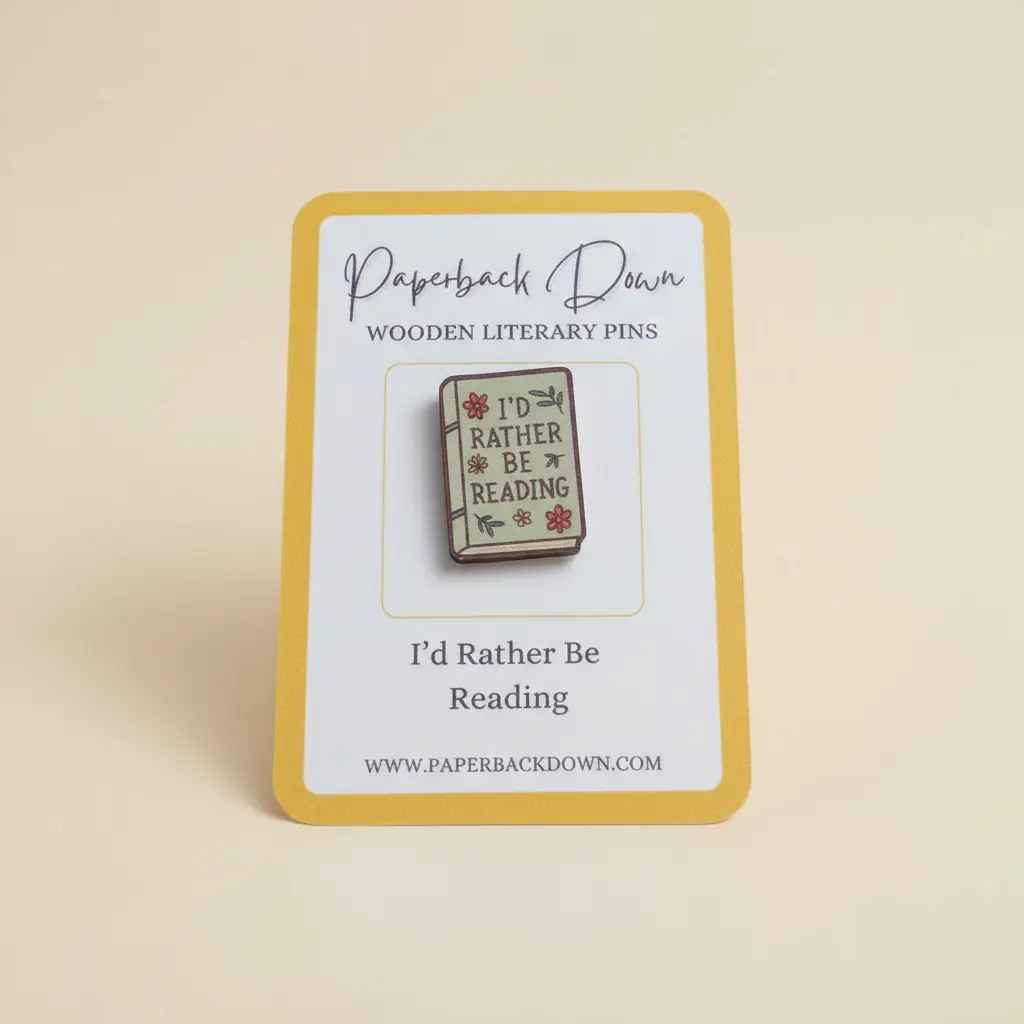 Wooden literary pin with 'I'd Rather Be Reading' design on a card, branded 'Paperback Down'.