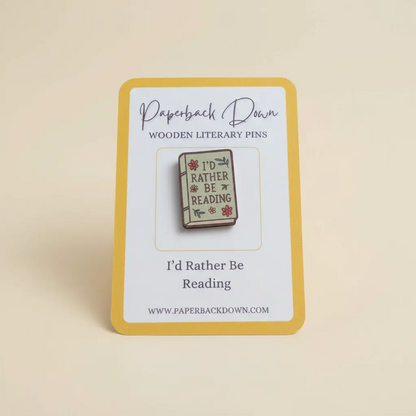Wooden literary pin with 'I'd Rather Be Reading' design on a card, branded 'Paperback Down'.